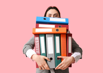 Wall Mural - Beautiful young businesswoman with folders on pink background