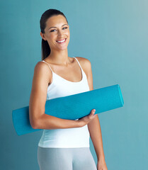 Canvas Print - Fitness, portrait and yoga with woman in studio isolated on blue background for health or wellness. Exercise, pilates and smile of happy person with mat for holistic training or physical improvement