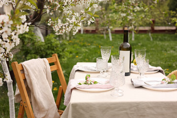 Canvas Print - Stylish table setting with beautiful spring flowers, wine, plates and glasses in garden