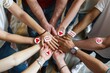 © CHAWA GEN - Hands with Blood Donation Stickers: A diverse group of people holding hands and wearing stickers that say 'World Blood Donor Day' or 'Blood Donor.'