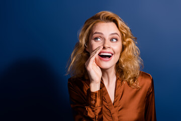 Wall Mural - Portrait of impressed girl with curly hairdo wear silk blouse tell secret looking empty space isolated on dark blue color background