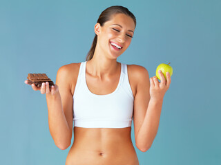 Wall Mural - Apple, chocolate and woman with healthy food choice isolated on studio, sugar and diet in blue background. Dessert, green fruit and young vegetarian person for detox, vegan or lose weight decision