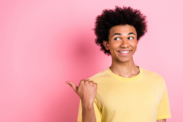 Sticker - Photo of funky dreamy man wear yellow t-shirt pointing thumb looking empty space isolated pink color background