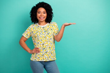 Photo of adorable lovely girl wear print t-shirt showing arm empty space isolated turquoise color background