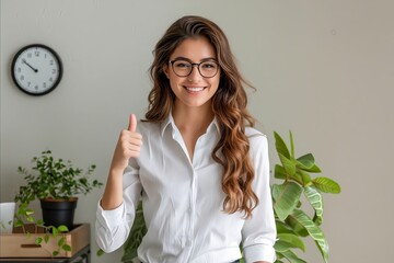 Poster - Young woman in glasses giving thumbs up in office.