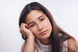 © HockleyMedia24/peopleimages.com - Studio portrait, teenager girl and bored or tired for fatigue and lazy with low energy. Female teen, annoyed expression and exhausted face with sleepy emoji for confused or sad by white background