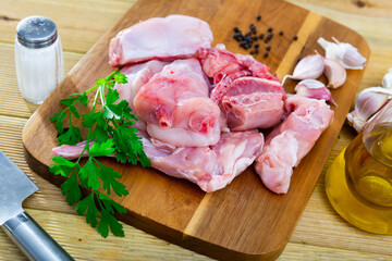 Wall Mural - Chopped fresh raw rabbit with greens, garlic and spices prepared for cooking on wooden cutting board. Healthy dietary food