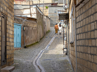 Ancient shell houses. The stone walls of the house are made of limestone blocks. Two women are walking along the street of the ancient city