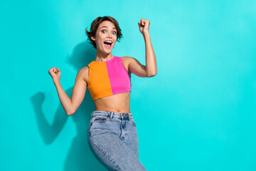 Wall Mural - Photo of impressed lucky woman wear pink orange top yelling yeah rising fists empty space isolated teal color background