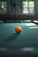 Wall Mural - A bright orange ball resting on the surface of a pool table, a common scene in billiard games