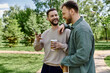 © Bliss - Two bearded men in casual clothing laugh together in a green park, enjoying a sunny day.