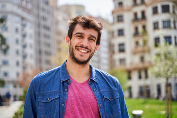 portrait of a happy young man on a city street looking at the camera