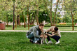© Bliss - Two bearded men in casual clothing happily interact with their Labrador Retriever in a green park.