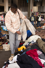 Wall Mural - South African guy selects second-hand clothes at a flea market