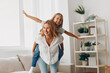 © SHOTPRIME STUDIO - Mother and daughter enjoy playful moment together stacking on top of each other in cozy living room