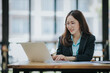 © Witoon - Young Asian professional business woman office worker analyst sitting at desk working on laptop thinking on project plan, analyzing marketing or financial data online, watching elearning webinar.