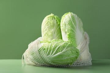 Wall Mural - Fresh Chinese cabbages in string bag on green background
