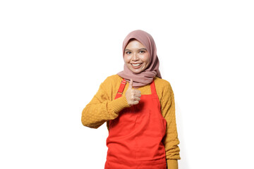 Wall Mural - Portrait of smiling woman in hijab and apron showing okay sign with hand isolated on white background.