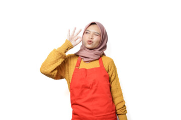 Wall Mural - Portrait of smiling woman in hijab and apron showing okay sign isolated on white background.