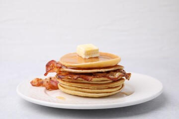 Wall Mural - Delicious pancakes with bacon, butter and honey on light table, closeup