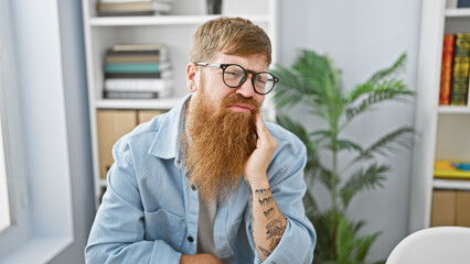 Handsome redhead business worker, a young man sitting in pain at the office table, suffering from toothache