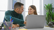 © Krakenimages.com - A man and woman engage as colleagues at a modern office, working together on a laptop in an amicable indoor environment.