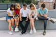 © anatoliycherkas - Group of teenagers sitting outdoors using their mobile phones.