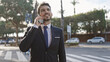 © Krakenimages.com - Handsome hispanic businessman in a suit on a mobile call outdoors with a blurred urban background