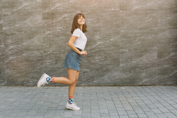 Wall Mural - Pretty teen girl with braces in glasses posing near gray wall