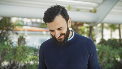 Wall Mural - Bearded man smiling leisurely in a lush garden setting under daylight