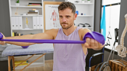 Sticker - Handsome man exercising with resistance band in a physiotherapy clinic