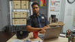 © Krakenimages.com - Handsome african american male police officer working on laptop in an office with evidence board.