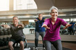 © ReadyAtTheEase/peopleimages.com - Mature group, woman and squat for exercise in gym, balance or coach for muscle development in class. Senior people, men and fitness for legs, smile or workout together in retirement at wellness club
