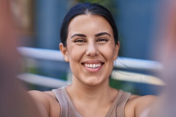 Wall Mural - Young beautiful hispanic woman smiling confident making selfie by camera at street