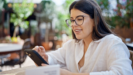 Poster - Young beautiful hispanic woman smiling happy using smartphone sitting on the table at bar terrace