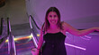 © Krakenimages.com - Smiling young woman in a casual black outfit at a purple-lit modern observatory with escalators