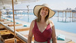 © Krakenimages.com - A smiling young woman in a stylish hat and swimwear enjoys a luxurious poolside setting at a seaside resort.