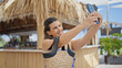 © Krakenimages.com - Young hispanic woman taking a selfie picture standing at sunny restaurant terrace