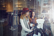 © peopleimages.com - Shopping, store and girl friends by clothes in retail mall for discount, sale or promotion. Style, window and young women bonding and buying designer outfit on rack at luxury fashion boutique.