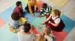© N Lawrenson/peopleimages.com - School, kids and teacher with game in circle for child development, activity and growth. High angle, hands and playful student on mat in kindergarten for sensory learning, creative skill or education