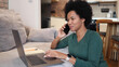 © PeopleVideos - African American woman working on her laptop at home and talking on mobile phone