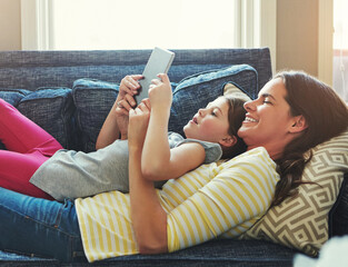 Mother, child and relax on sofa with tablet for online streaming service, movies or ebook reader on holiday. Happy family, woman or mom with daughter on lounge and digital tech for e learning at home