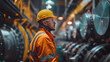 © khonkangrua - Male industrial worker wearing a hard hat and safety gear, inspecting equipment in a large industrial facility.