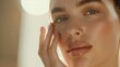 © r3mmm - Close-up of a woman with radiant skin, gently touching her face, illuminated by warm, natural light.