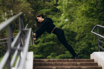 Wall Mural - Young woman warming up, stretching her muscle at the stairway. Fit runner workout and warming up at top of stairs.