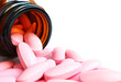 © jobi_pro - Closeup of pink tablets scattered from a glass bottle on white background