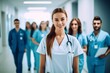 © olegganko - Smiling Female Nurse Leading Group of Medical Professionals Down Hospital Corridor