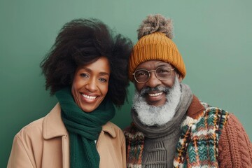 Wall Mural - Portrait of a smiling afro-american couple in their 60s donning a warm wool beanie in pastel green background