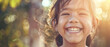 © Ai Studio - A young girl with a radiant smile beams with pure joy against a sun-dappled, blurry backdrop, capturing the essence of innocent happiness.