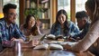 © Ilia Nesolenyi - A group of friends, representing a range of ethnicities, are gathered around a table, intently focused on a Bible study session. The image captures a moment of shared learning and fellowship